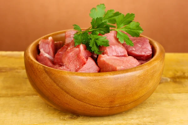 Rohes Rindfleisch in Schüssel auf Holztisch auf braunem Hintergrund — Stockfoto
