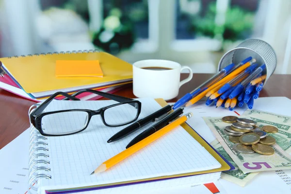 Material de escritório com documentos e xícara de café na mesa em fundo brilhante — Fotografia de Stock