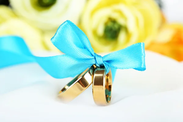 Anéis de casamento amarrados com fita em tecido branco — Fotografia de Stock