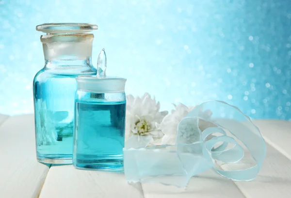 Glass bottles with color essence, on wooden table, on blue background — Stock Photo, Image