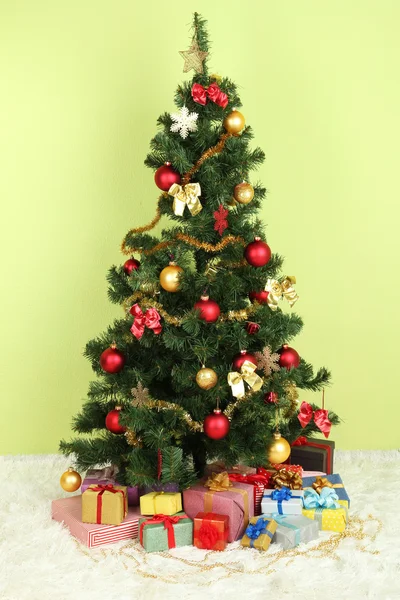 Decorated Christmas tree with gifts on green wall background — Stock Photo, Image