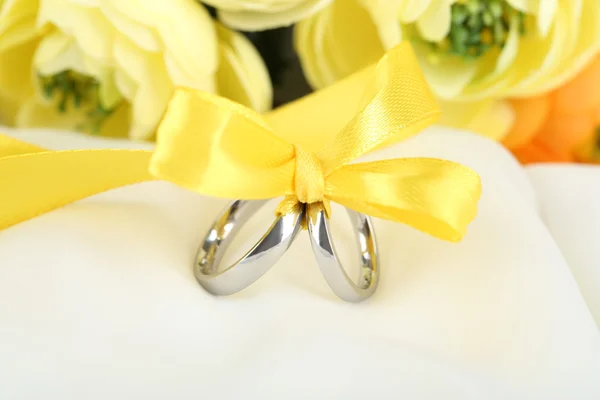 Anillos de boda atados con cinta en tela blanca — Foto de Stock