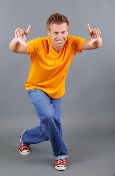 Knappe jongeman dansen op grijze achtergrond — Stockfoto