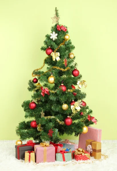 Decorated Christmas tree with gifts on green wall background — Stock Photo, Image