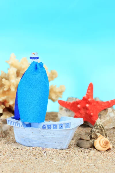 Blaues Spielzeugschiff auf Sand, auf blauem Hintergrund — Stockfoto