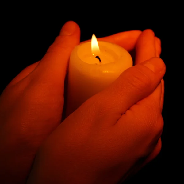 Burning candle in hands isolated on black — Stock Photo, Image