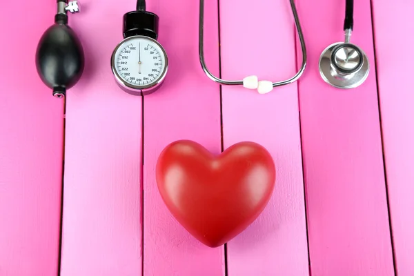 Tonometer, stethoscope and heart on wooden table close-up — Stock Photo, Image