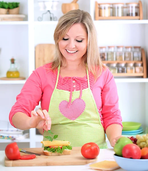 Happy smiling woman in kitchen preparing sandwich — Stock Photo, Image