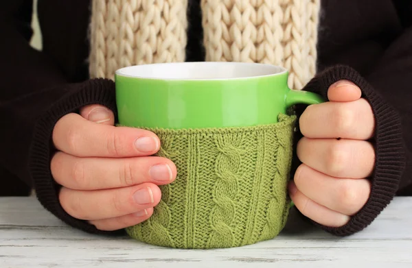 Cup with knitted thing on it in female hands close up — Stock Photo, Image