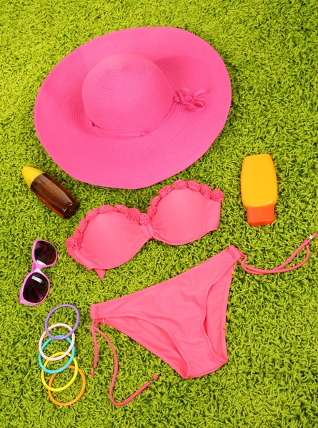 Swimsuit and beach items on green background — Stock Photo, Image