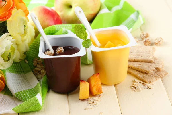 Tasty cream desserts with pieces of fresh fruits, cookies and flakes,on color wooden background — Stock Photo, Image