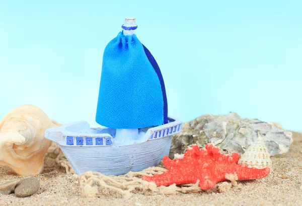 Blauwe speelgoed schip op zand, op blauwe achtergrond — Stockfoto