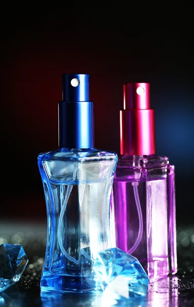 Perempuan parfum dalam botol indah di latar belakang gelap dengan cahaya warna — Stok Foto