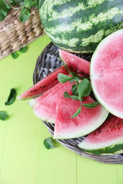 Rijp watermeloenen in rieten-lade op houten tafel — Stockfoto