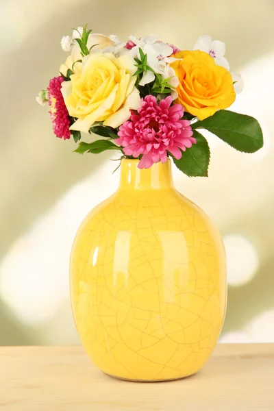 Mooi boeket van heldere bloemen in kleur vaas, op houten tafel, op lichte achtergrond — Stockfoto