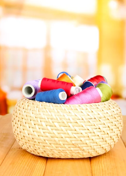 Panier en osier avec accessoires pour la broderie sur table en bois, sur fond lumineux — Photo