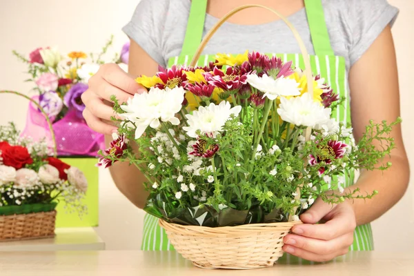 Florista faz buquê de flores em cesta de vime — Fotografia de Stock