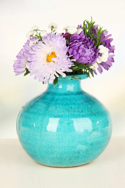 Hermoso ramo de flores brillantes en jarrón de color, sobre mesa de madera, sobre fondo brillante — Foto de Stock