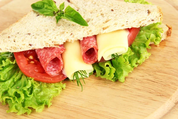 Sándwich sabroso con salchichas de salami y verduras en la tabla de cortar, primer plano — Foto de Stock