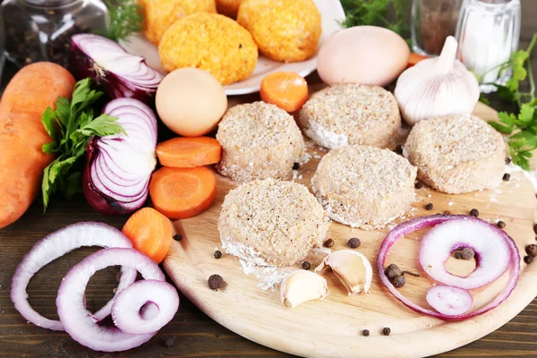 Meat patties on board on wooden table — Stock Photo, Image