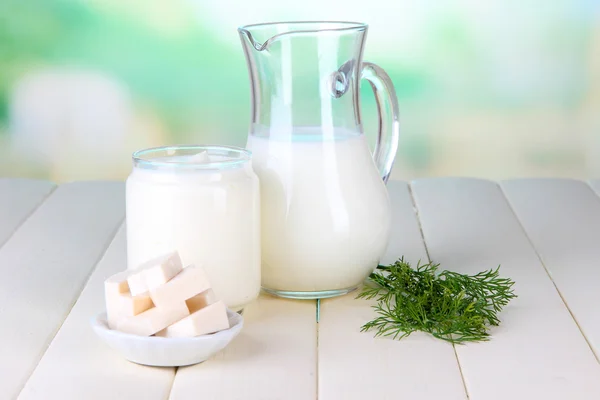 Frische Milchprodukte auf Holztisch vor natürlichem Hintergrund — Stockfoto