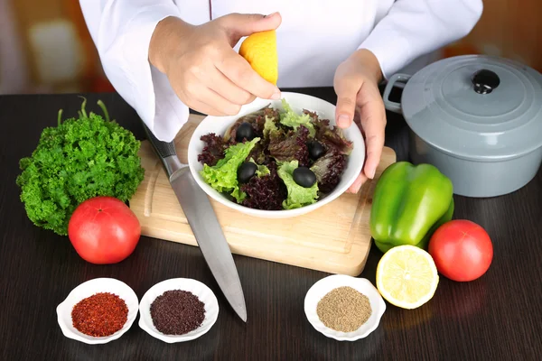 Cook hands squeezing lemon into salad — Stock Photo, Image