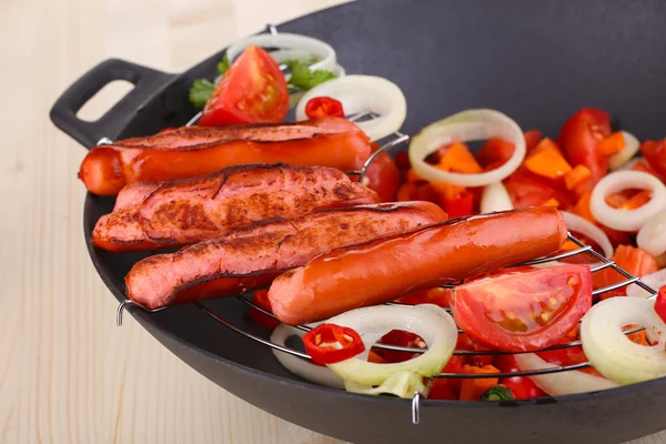 Salsichas deliciosas com legumes em wok na mesa de madeira close-up — Fotografia de Stock