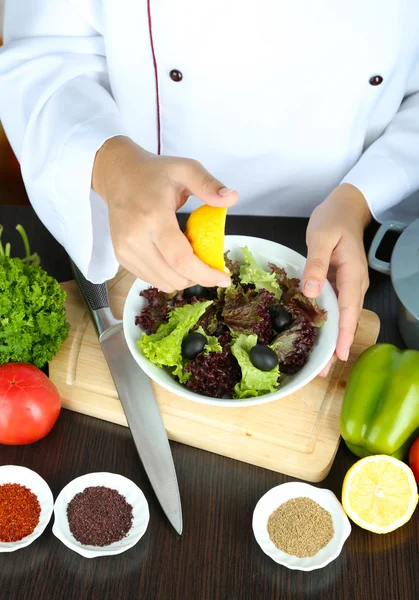 Koken handen knijpen citroen in salade — Stockfoto