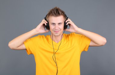 yakışıklı genç adam gri arka planda müzik dinlemek