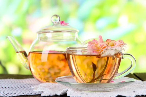 Vattenkokare och kopp te från tea rose på servett på träbord på natur bakgrund — Stockfoto