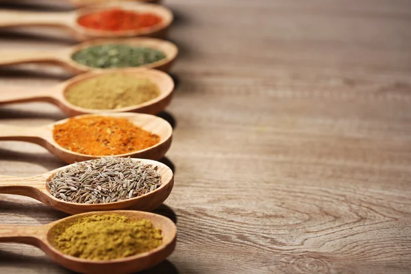 Assortment of spices in wooden spoons on wooden background — Stock Photo, Image