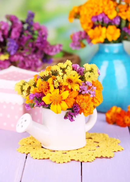 自然の背景に木製のテーブルの上の水まき缶でマリーゴールドの花の花束 — ストック写真