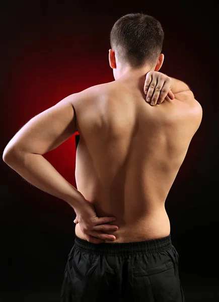 Young man with back pain, on red background — Stock Photo, Image