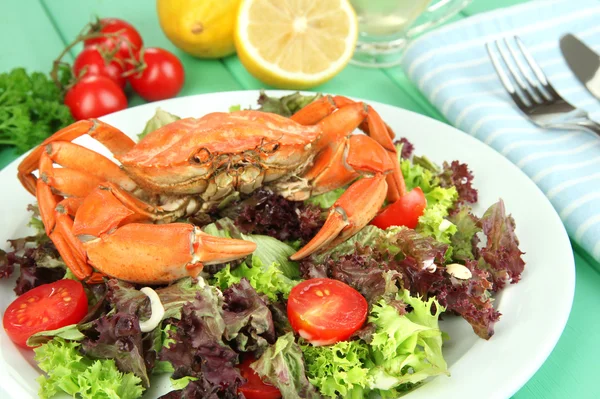 Gekookte krab op wit bord met salade bladeren en tomaten, op houten tafel achtergrond — Stockfoto