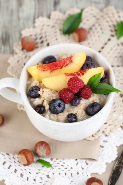Oatmeal in cup with berries on napkins on wooden table — Stock Photo, Image