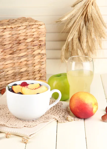 Oatmeal in cup with berries on napkins on wooden table on bright background — Stock Photo, Image