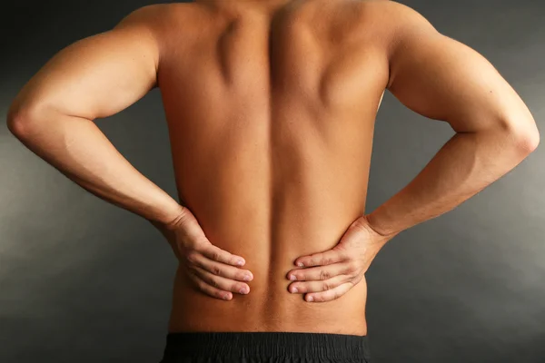 Young man with back pain on grey background — Stock Photo, Image