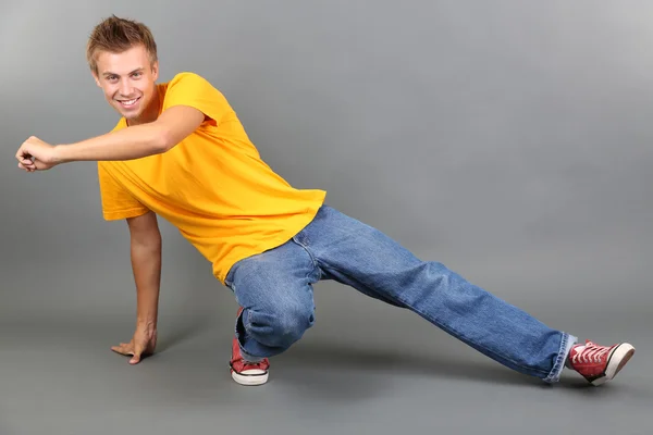 Pohledný mladý muž tančí na šedém pozadí — Stock fotografie