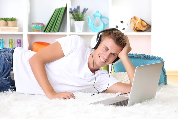 Jeune homme relaxant sur tapis avec ordinateur portable — Photo