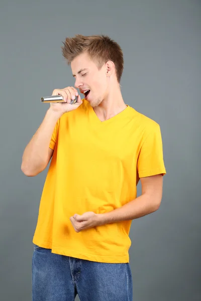 Knappe jonge man zingt op grijze achtergrond — Stockfoto