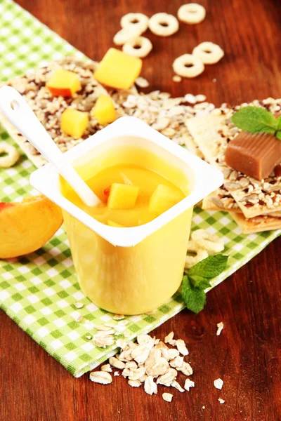 Smaczny jogurt z kawałkami świeżych owoców, ciasteczka i płatków, na tle drewniane — Zdjęcie stockowe
