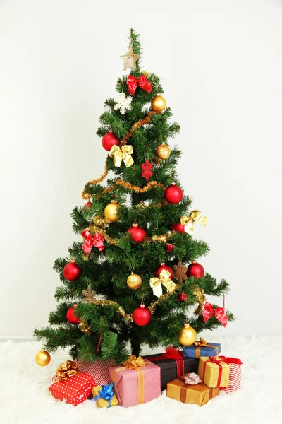 Geschmückter Weihnachtsbaum mit Geschenken auf grauem Wandhintergrund — Stockfoto