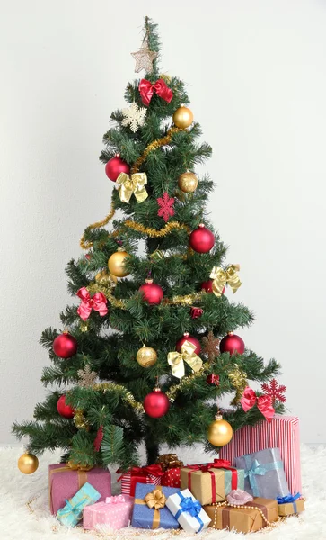 Noel ağacı duvar gri arka plan üzerinde hediyeler ile dekore edilmiş — Stok fotoğraf