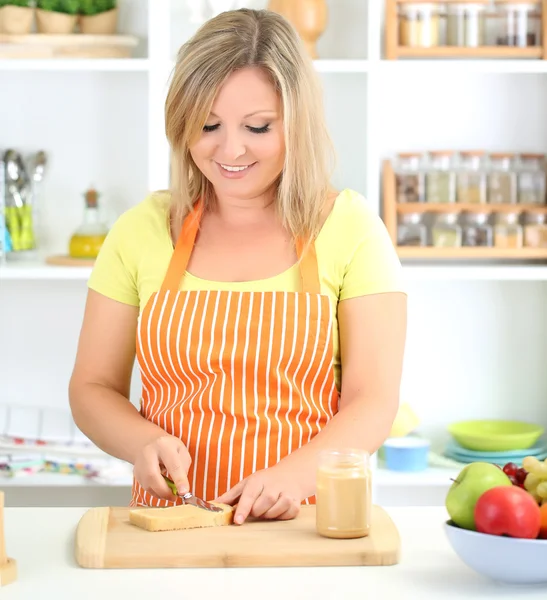 Happy smiling woman in kitchen preparing sandwich — Stock Photo, Image