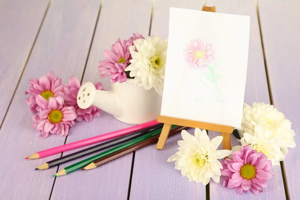 Composition of flowers and small easel with picture on wooden table close-up — Stock Photo, Image