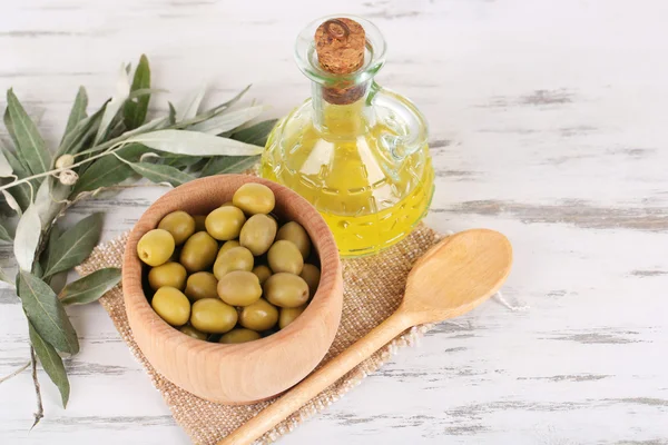 Olive oil and olives in bowl on sackcloth wooden table — Stock Photo, Image