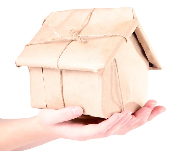 Mains de femme tenant une maison enveloppée dans du papier kraft brun, isolé sur du blanc — Photo