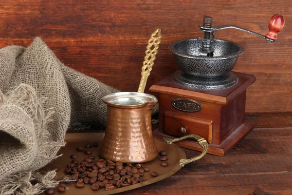 Mlýnek na kávu, Turek a kávová zrna na zlatém podnosu na dřevěné pozadí — Stock fotografie