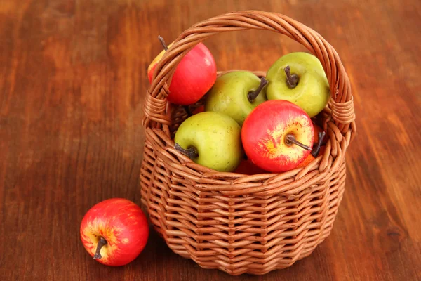 Small apples in wicker basket on wooden background — Stock Photo, Image
