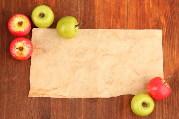 Старая бумага и маленькие яблоки на деревянном фоне — стоковое фото